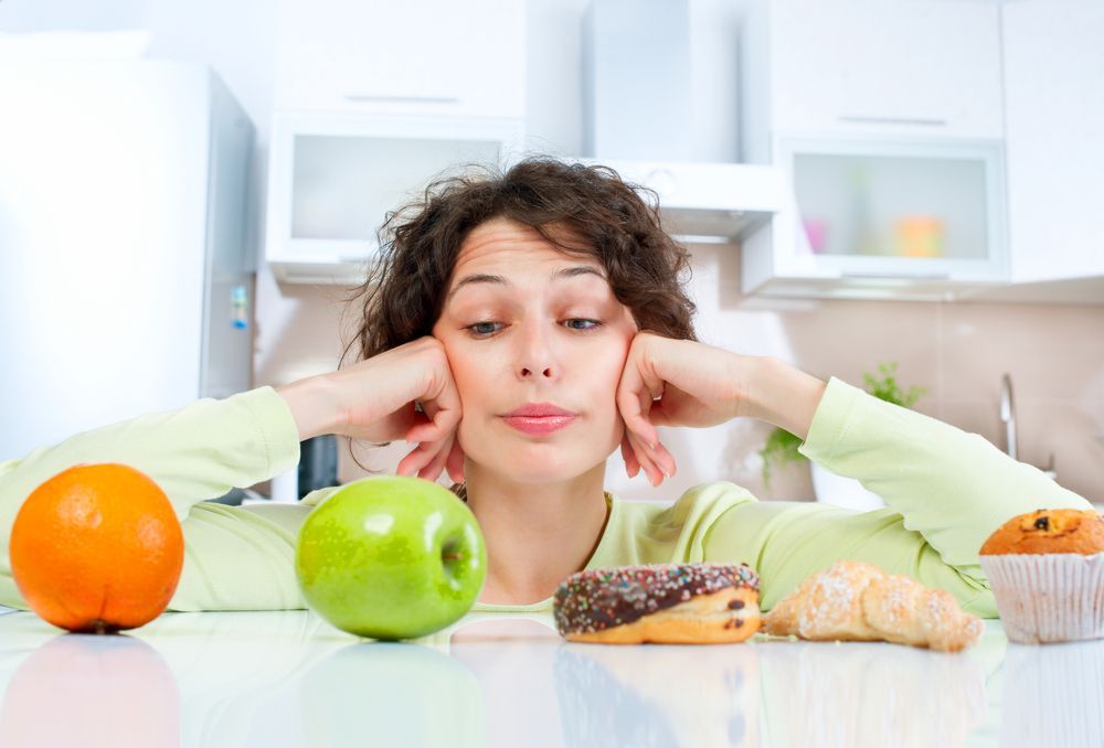 mujer contempla unas piezas de fruta y bollería