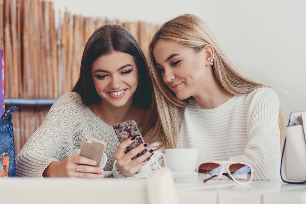Dos mujeres sonríen y miran su teléfono móvil