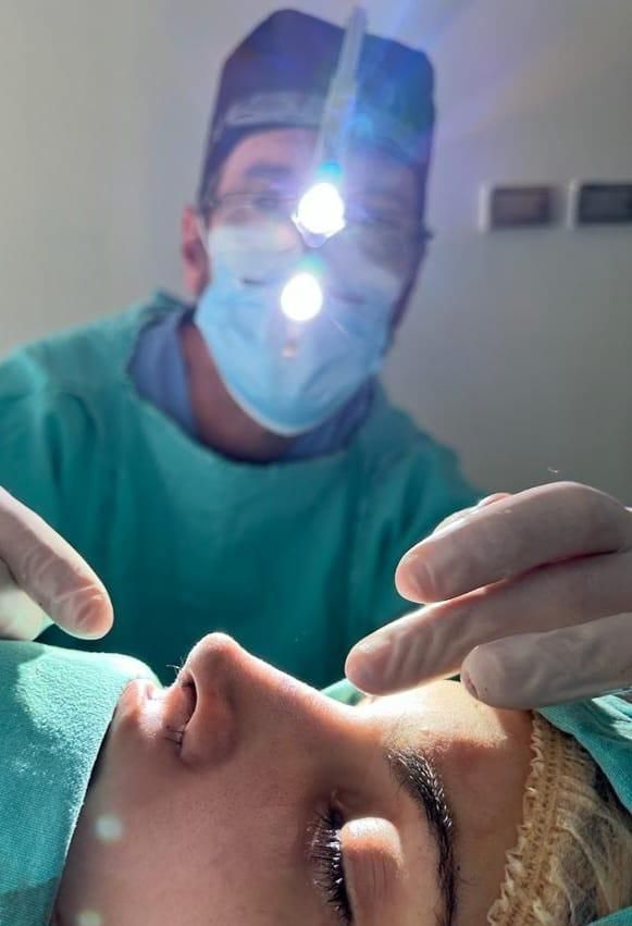 Doctor revisa la nariz de una paciente durante la cirugía de rinoplastia
